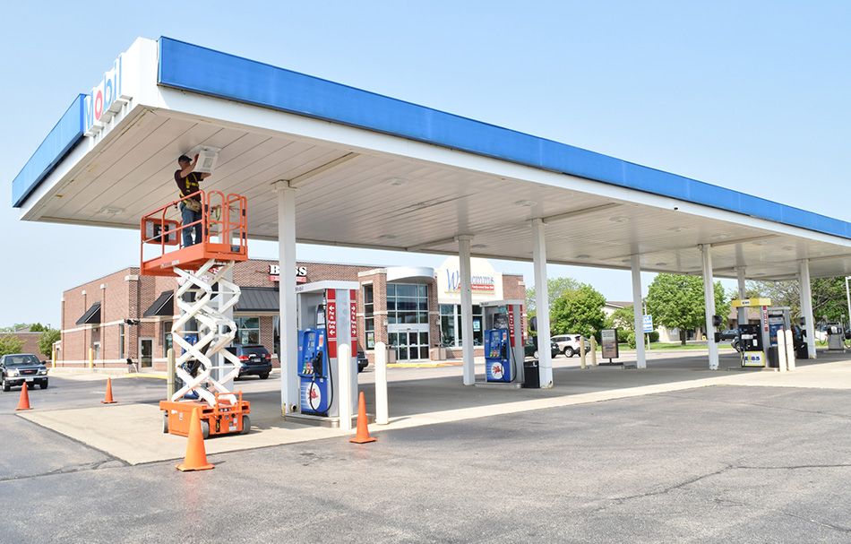 man in a scissor lift at a gas station installing lighting in the canopy covering gas pumps