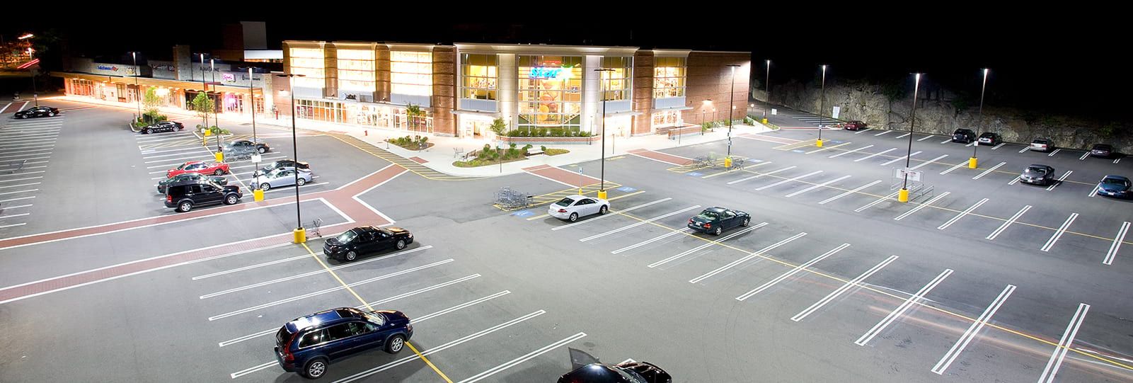 Retail store parking lot that is well lit with storefront lighting fixtures